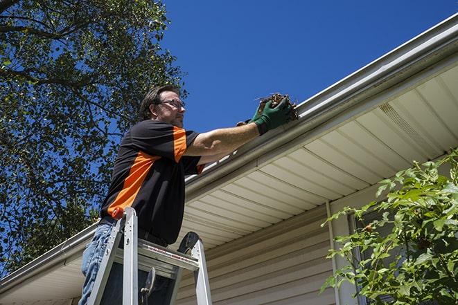 repairman using a ladder to access a damaged gutter for repair in Agoura Hills